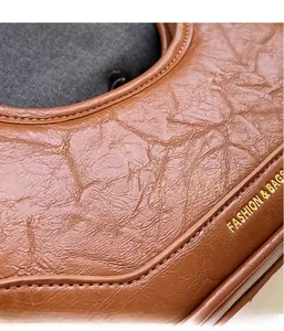 Detail of brown pleated leather texture and golden Fashion & Bags logo on the handbag