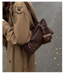 Close-up of retro brown suede tote bag with matching pouch and silver metal rivet details
