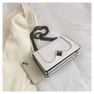 Detail of white snake-embossed flap bag with gunmetal chain and diamond turn-lock