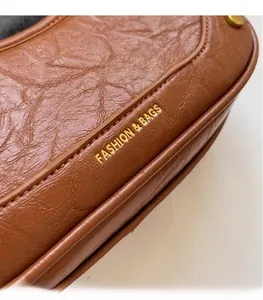 Detail shot of pleated caramel leather bag with gold-stamped FASHION & BAGS lettering