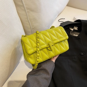 Bright yellow quilted crossbody bag with chain strap and round magnetic closure