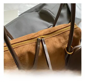 Detailaufnahme der braunen Wildleder-Rundtasche mit hochwertigen goldenen Metallreißverschlüssen