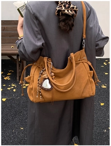 Detail of tan large-capacity tote bag with leopard heart charm in an autumn setting