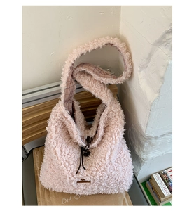 Close-up of pink faux shearling tote bag with drawstring closure and plaid strap lining