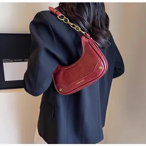 Detail of burgundy crescent shoulder bag with gold chain and leather strap