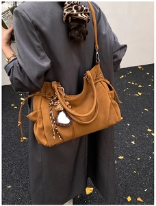 Detail of tan tote bag featuring side drawstrings and leopard print heart charm