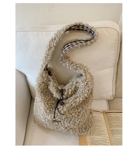 Detail of beige fleece tote bag with brown drawstring and leather logo on white sofa