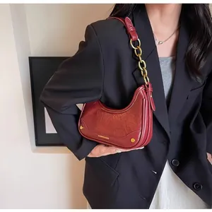 Detail of burgundy crescent shoulder bag with glossy leather and gold chain strap