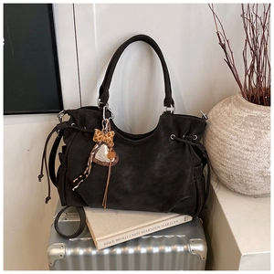 Detail of black matte tote bag with leopard bow heart charm on a silver suitcase