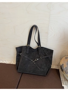 Detail of black matte tote bag featuring dual shoulder straps and metal buckle accents
