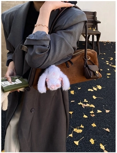 Nahaufnahme einer braunen Wildleder Boston Handtasche mit süßen Anhängern im Winter