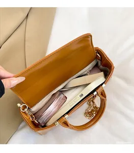 Macro view of warm brown crossbody bag interior showing spacious main compartment and zip pocket