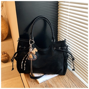 Close-up of black matte tote bag with drawstring details and plush leopard charm