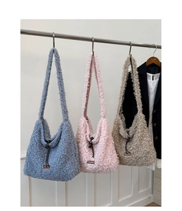 Hanging fuzzy sherpa tote bags in grey-blue, pink, and khaki showing soft wool textures