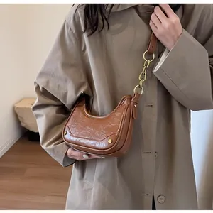 Detail of vintage brown crescent bag with pleated leather and gold chain strap