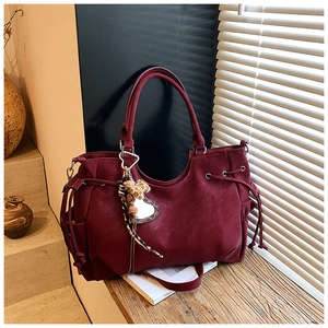 Macro detail of wine red retro tote bag with drawstring accents and leopard heart charm