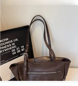 Detail view of deep brown leather tote bag with adjustable buckle and top zipper pocket