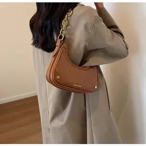 Detailed view of brown oil-wax leather crescent bag with chunky gold chain strap