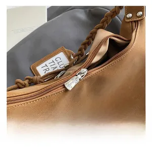 Détails du zip argenté et de la poignée tressée sur un sac à bandoulière marron chic