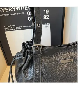 Close-up of black lychee grain leather texture and adjustable strap with silver eyelets