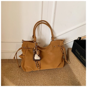 Detail of brown faux leather tote bag with side drawstring and leopard heart charm