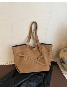 Close-up of vintage brown leather tote bag showing grainy texture and gold buckle detail