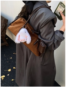 Detail einer braunen Wildleder-Schultertasche mit Plüschkaninchen und rundem Münzfach