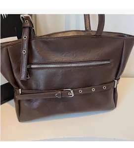 Detail of dark brown faux leather shoulder bag with decorative metal zipper and eyelet belt
