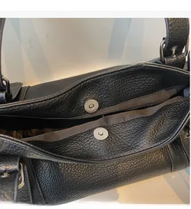 Detail of black pebbled leather tote showing magnetic closure and silver hardware parts