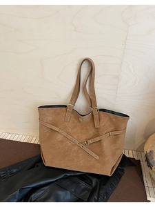 Detailed macro view of the brown textured leather tote with cross strap and metal buckle
