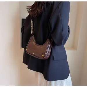 Detail of vintage brown crescent bag with gold chain strap on model's shoulder
