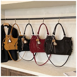Detailed row of tote bags in ginger, black, wine red and grey with decorative tassels