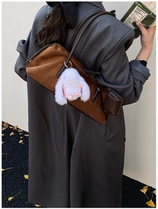 Detail einer braunen Wildleder-Tote-Bag mit Plüschhasen-Anhänger an der Schulter