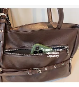 Close-up of brown faux leather tote bag showing a front zipper pocket with a phone inside