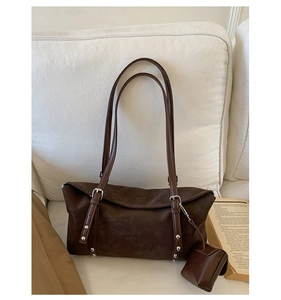 Detail of dark brown matte tote bag with silver buckles and a matching small pouch