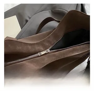 Detail of silver zipper and matte leather texture on a dark brown tote shoulder bag