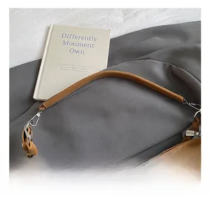 Détail de la poignée en cuir marron du sac et de son crochet en métal argenté