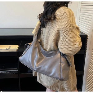 Detail view of a large grey hobo tote bag with functional side flap pockets for women