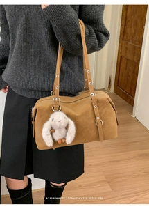 Dettaglio della borsa tote retrò marrone con occhielli in metallo e ciondolo a forma di coniglio