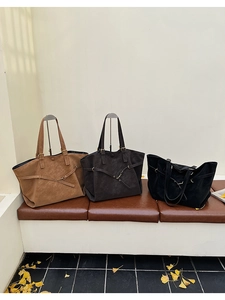 Three large vintage tote bags in tan, dark brown, and black displayed on a leather bench