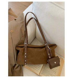 Detail of dark brown suede shoulder bag with rivets and mini pouch on sofa