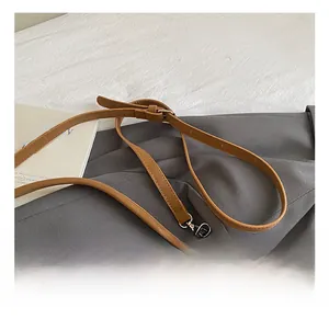 Détail de la bandoulière réglable en cuir marron avec texture tissée et boucle en métal