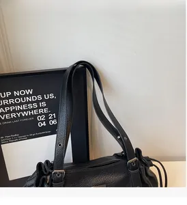 Detail of lychee pattern leather texture with silver metal buckles on a black tote bag