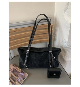 Detail of black suede tote bag with metal rivet straps and hanging mini coin pouch