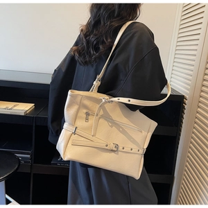 Detail of off-white leather tote bag with functional silver zippers and adjustable straps