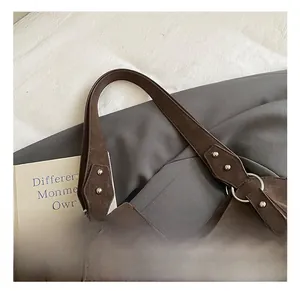 Detail of dark brown vintage tote bag handle with silver ring and rivet reinforcements