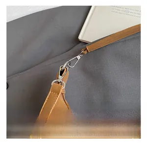 Détail du crochet métallique argenté et de la bandoulière sur sac en cuir marron