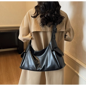 Détail d'un grand sac fourre-tout noir en cuir souple avec deux poches latérales à rabat