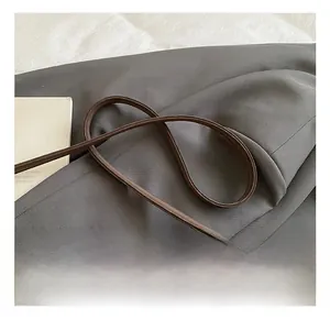 Detail of adjustable shoulder strap with metal hook on a dark brown suede tote bag