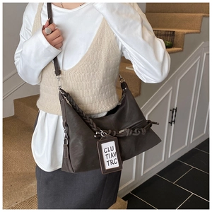 Détail du sac hobo marron foncé avec des nœuds tissés épais et une étiquette carrée